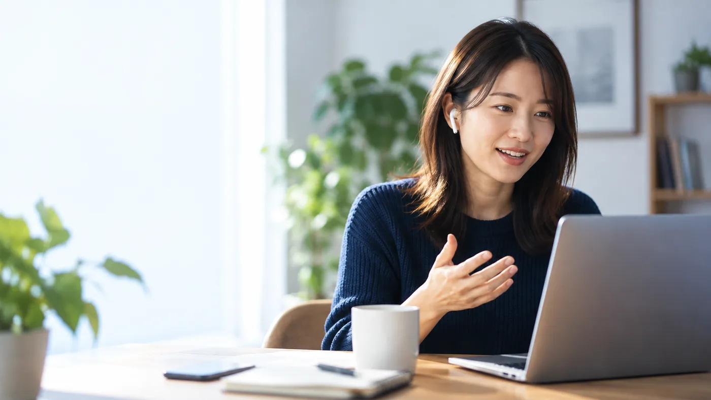 イヤホンを着けてノートパソコンでオンライン英語学習をする女性